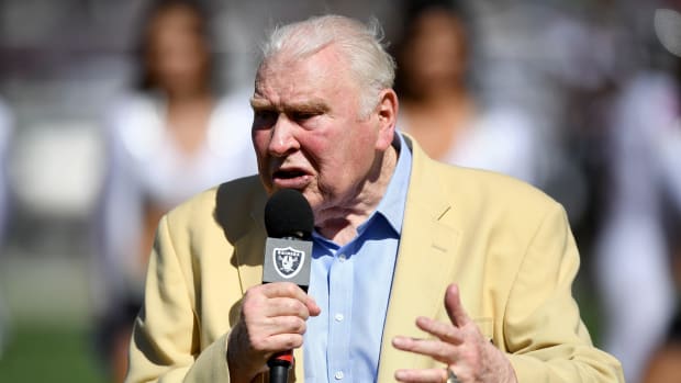 John Madden holds a microphone and speaks before a game.