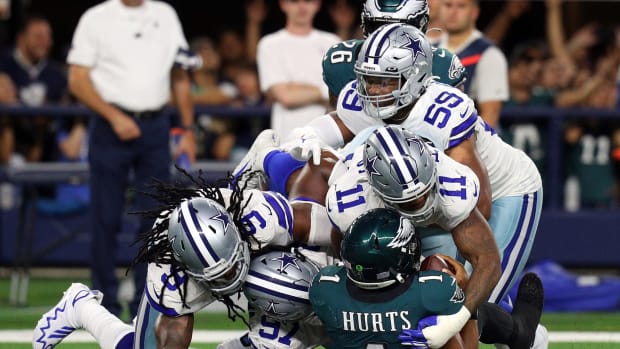 The Cowboys defense swarms and sacks Eagles quarterback Jalen Hurts.
