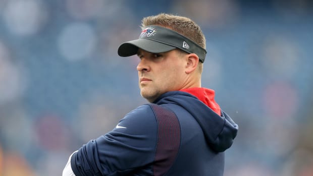 Former New England Patriots offensive coordinator Josh McDaniels looks over his shoulder with his arms crossed.