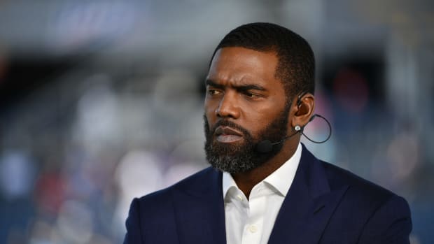 Former NFL wide receiver Randy Moss looks on.