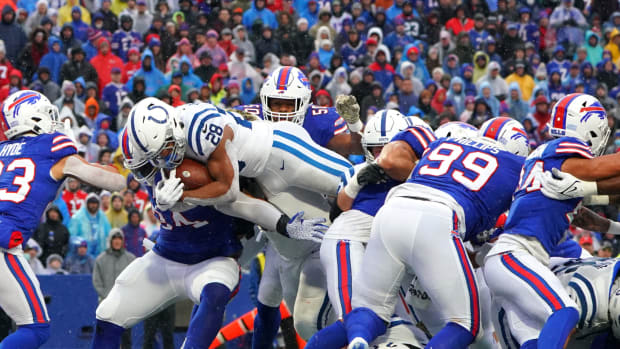 Colts running back Jonathan Taylor dives into the end zone while surrounded by Bills tacklers.