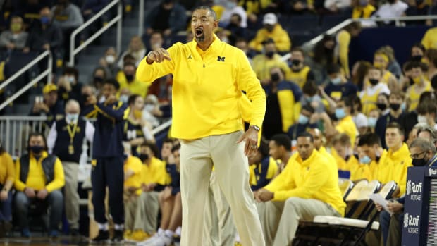 Juwan Howard coaching on the sidelines during a Michigan basketball game.