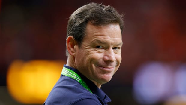 Jim Mora smirks at the camera while on the sidelines during a game.