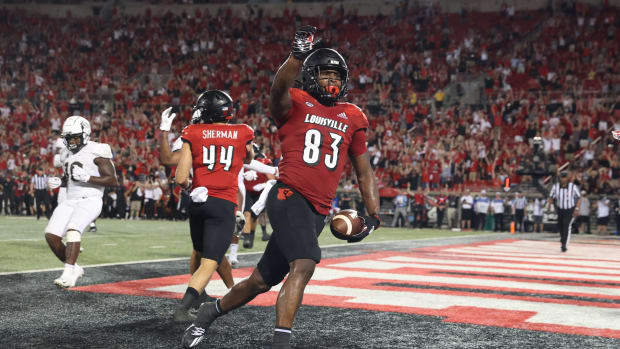 A Louisville player points to the crowd after scoring a touchdown.