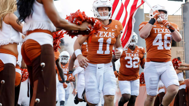 Texas linebacker Jake Ehlinger runs onto the field with the American flag alongside brother Sam Ehlinger.