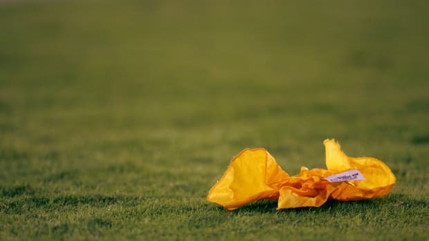 A closeup of a penalty flag on a football field.