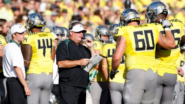Chip Kelly talks to two players during a game.