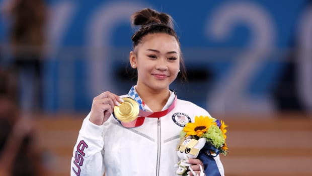 Suni Lee shows off her gold medal in the individual all-around.