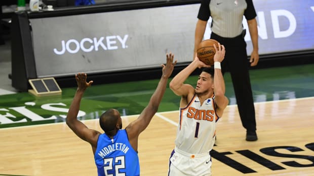 Devin Booker of the Phoenix Suns shoots a jumper over Khris Middleton of the Milwaukee Bucks.