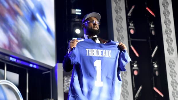 A picture of Kayvon Thibodeaux holding up a No. 1 Giants jersey on stage after being drafted.