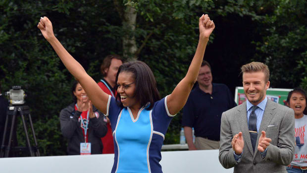 CROPPED VERSION
US First Lady Michelle Obama raises her arms as British footballer David Beckham (R) applauds during a football game with children as part of the "Let's Move-London" event at the Winfield House in London on July 27, 2012, hours before the official start of the London 2012 Olympic Games.   AFP PHOTO / JEWEL SAMAD        (Photo credit should read JEWEL SAMAD/AFP/GettyImages)
