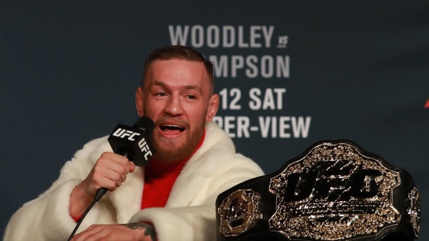 Conor McGregor talking into a microphone next to his UFC belt.