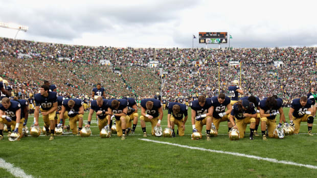 Notre Dame players kneeling on the sideline.