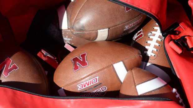 A bag of footballs with the logo of the Nebraska Cornhuskers.