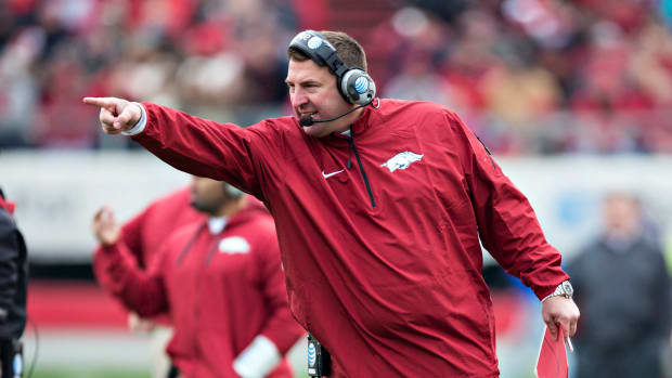 Bret Bielema pointing while wearing a red Arkansas jumpsuit.