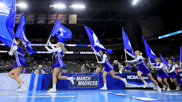 Kentucky Wildcats cheerleaders running onto the basketball court.