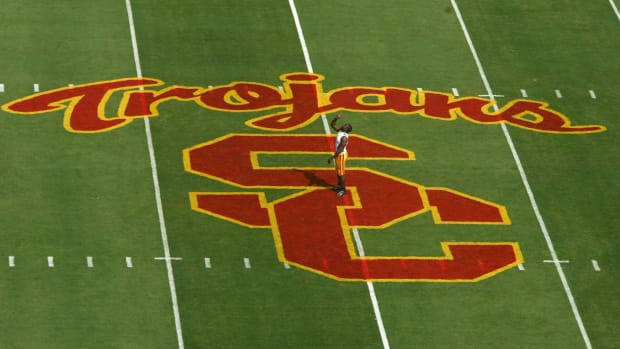 A player stading at the 50 yard line of USC's football field.
