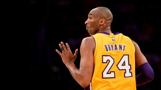 Kobe Bryant holding out five fingers as he runs up the floor.