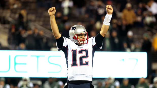 New England Patriots QB Tom Brady raising his arms in triumph after an NFL win.