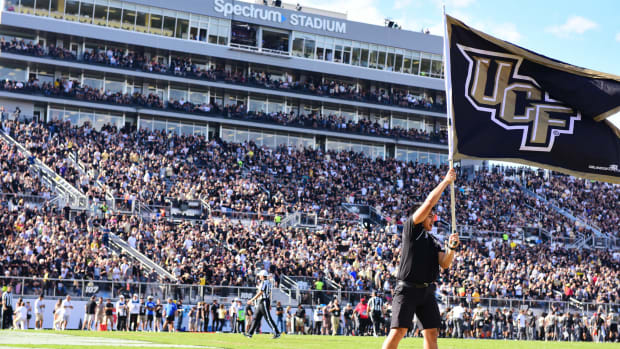 A man holding a UCF flag in the air.