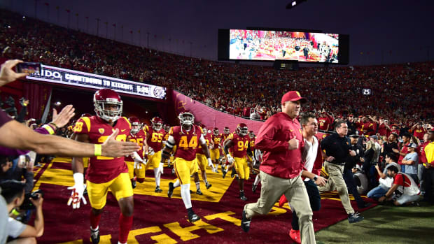 Clay Helton running onto the field with the USC football team.