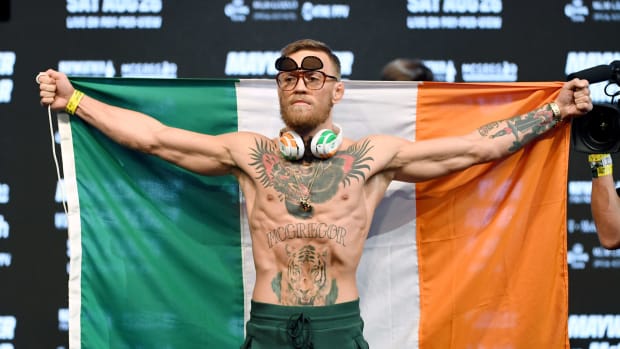 Conor McGregor wearing headphones and sunglasses while holding the Irish flag.