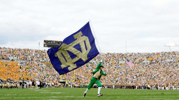 Notre Dame's mascot running with a flag on the football field.