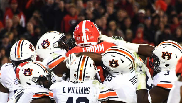 Auburn football players tackling Jake Fromm during an SEC college football rivalry game.