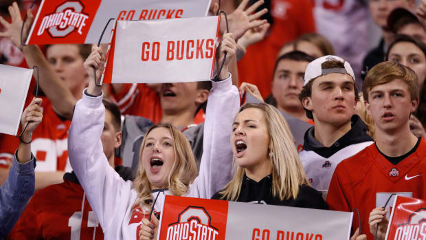 Ohio State fans holding Go Bucks signs during a football game.