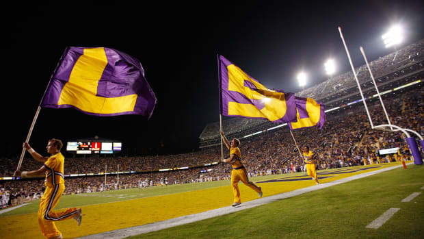 LSU cheerleaders run around the field with flags.