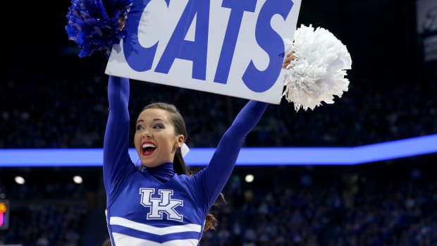 A Kentucky cheerleader holding up a sign that says Cats.
