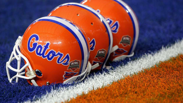 Three Florida Gators football helmets on the field.