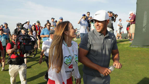 Brooks Koepka walking on the golf course with his girlfriend.