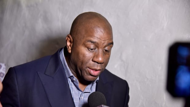 Magic Johnson speaks with reporters at an event.
