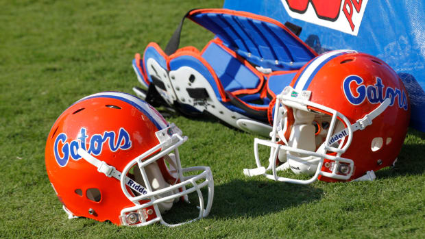 Two Florida Gators helmets sitting on the field.