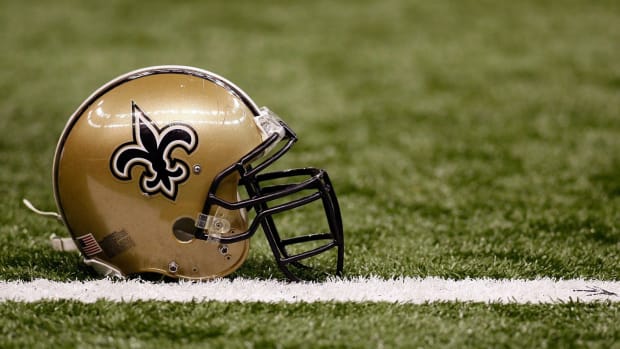 A closeup of a New Orleans Saints helmet on the football field.