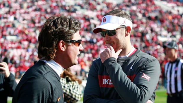 Mike Gundy and Lincoln Riley speak on the field before a game.