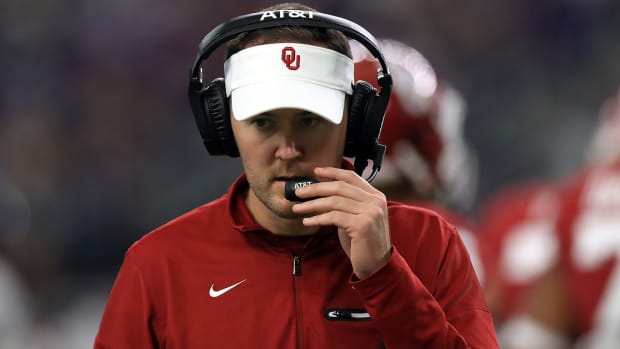 A closeup of Oklahoma Sooners coach Lincoln Riley talking into his headset.