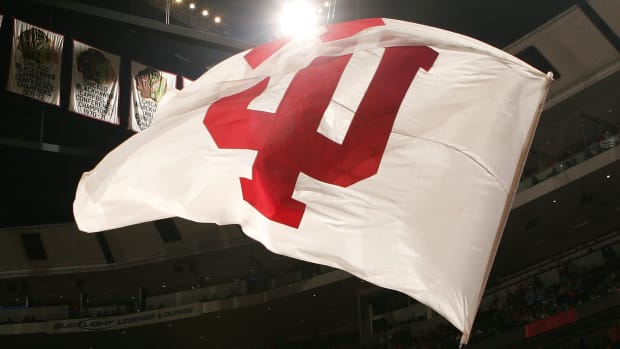 A cheerleader from the Indiana Hoosiers waves a flag with Indiana's logo on the court against the Illinois Fighting Illini.