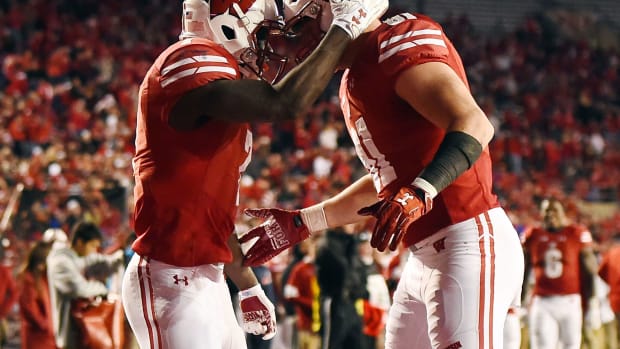 Two Wisconsin including running back Bradrick Shaw players bang helmets to celebrate a touchdown.