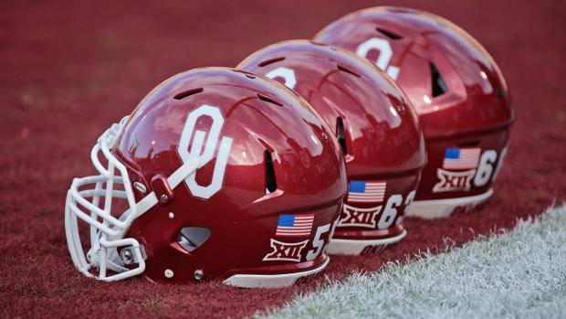 A closeup of three Oklahoma Sooners football helmets on the field before a football game.