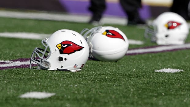 Three Arizona Cardinals helmets sitting on the field.