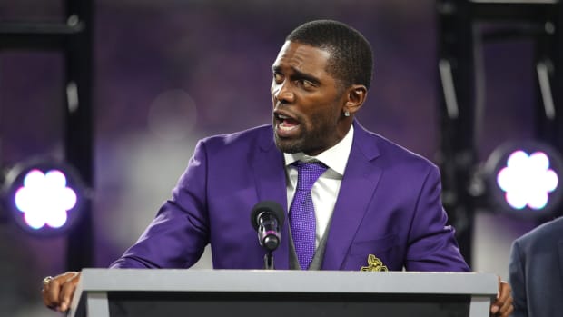 Randy Moss speaking at a podium.