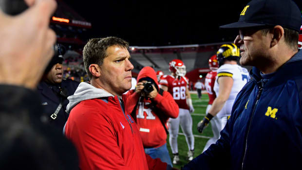 Jim Harbaugh shaking hands with Chris Ash following a football game.