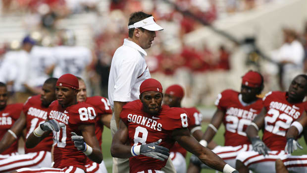 Bob Stoops walking by his players as they stretch.