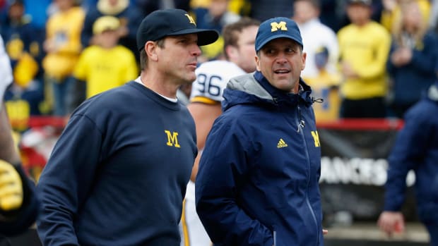 Head coach Jim Harbaugh of the Michigan Wolverines (L) jogs off the fiedl with his brother Baltimore Ravens head coach John Harbaugh (R) following halftime of the Michigan and Maryland Terrapins.
