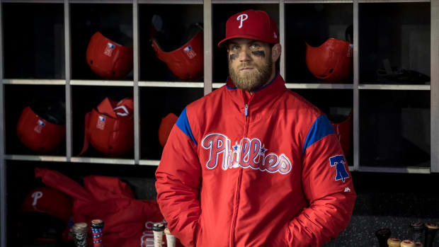Bryce Harper standing in the dugout wearing his Phillies jacket.