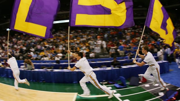lsu cheerleaders run onto the field holding 'lsu' flags