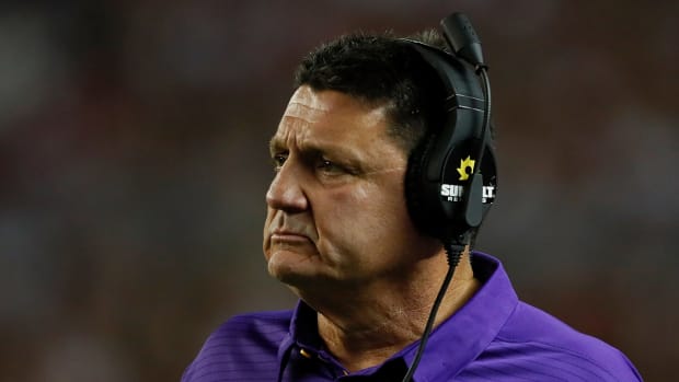 LSU football coach Ed Orgeron wearing a headset and a concerned look.