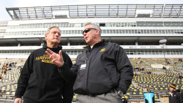 Gary Barta and Kirk Ferentz talk on the Iowa football field.